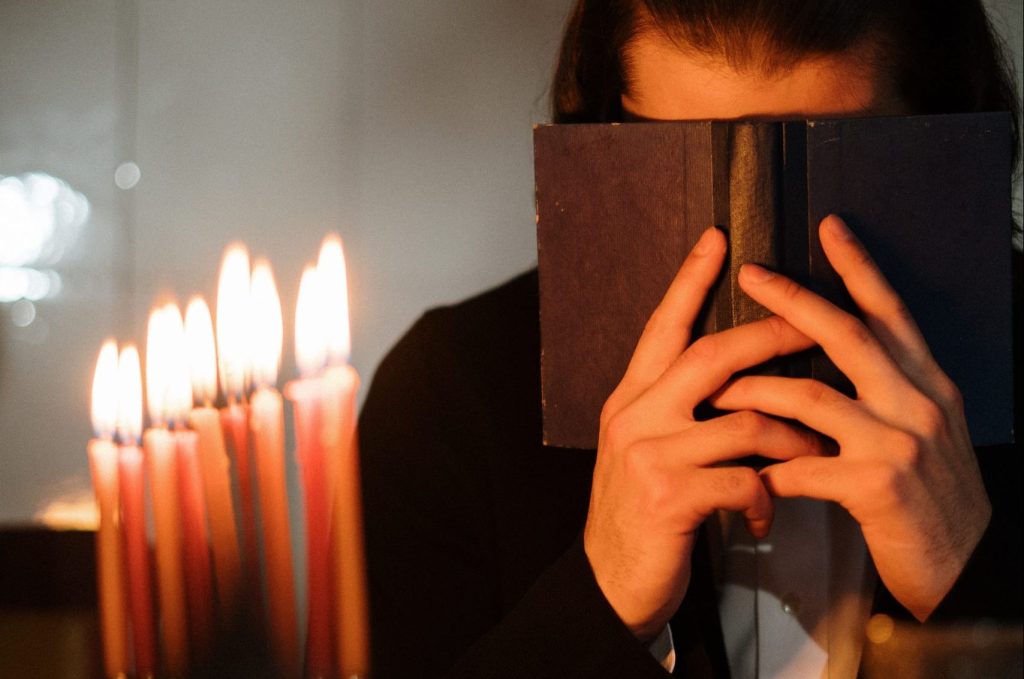 man covering his face with bible while praying
