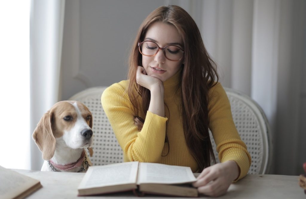 woman reading a book with a dog