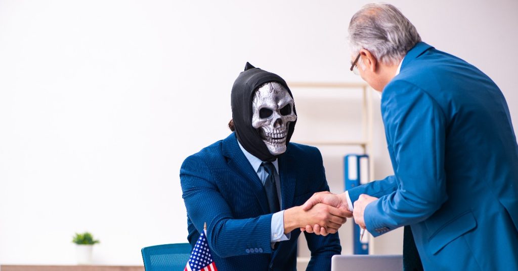 man shaking hands with someone wearing skeleton mask